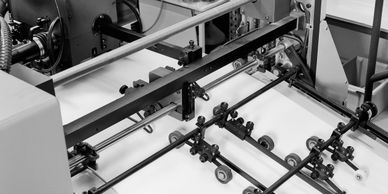 Industrial printing machine feeding blank sheets of paper for processing.