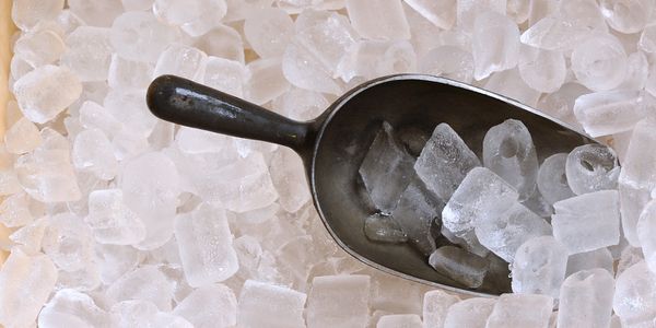 Metal scoop filled with ice cubes on a bed of ice.