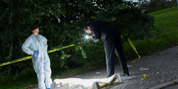 Investigators examine a crime scene at night.