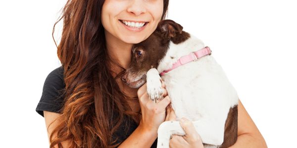Smiling woman holding a small dog with a pink collar.
