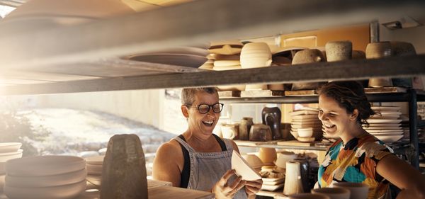 Two people happily discussing pottery in a workshop.