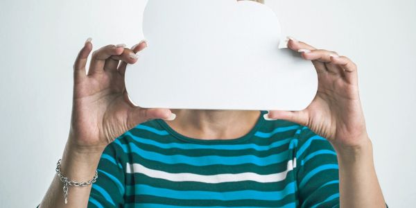 Person holding a cloud-shaped cutout in front of their face.