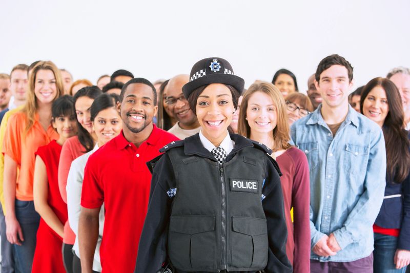 Retrato de una mujer policía sonriente frente a una gran multitud