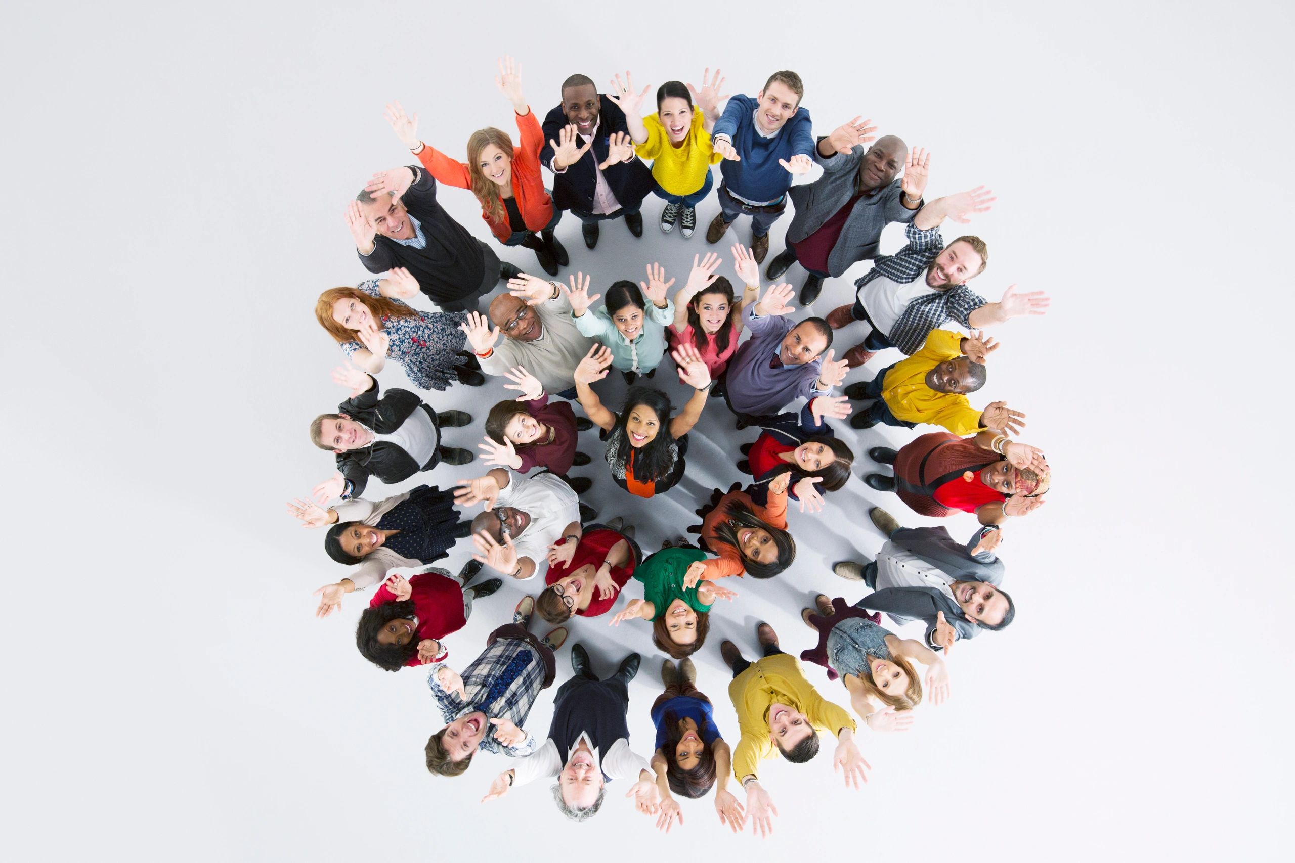 Diverse group of people standing in a circle, looking up and waving.