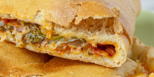 Close-up of a stuffed calzone with herbs and cheese.