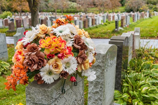 This image shows a close-up of a floral arrangement placed on a headstone in a cemetery