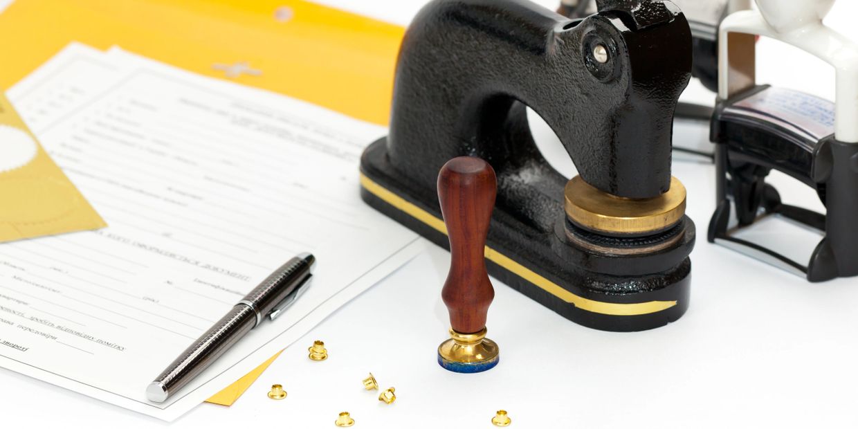 Office desk setup with stamps, documents, pen, and envelopes ready for processing.
