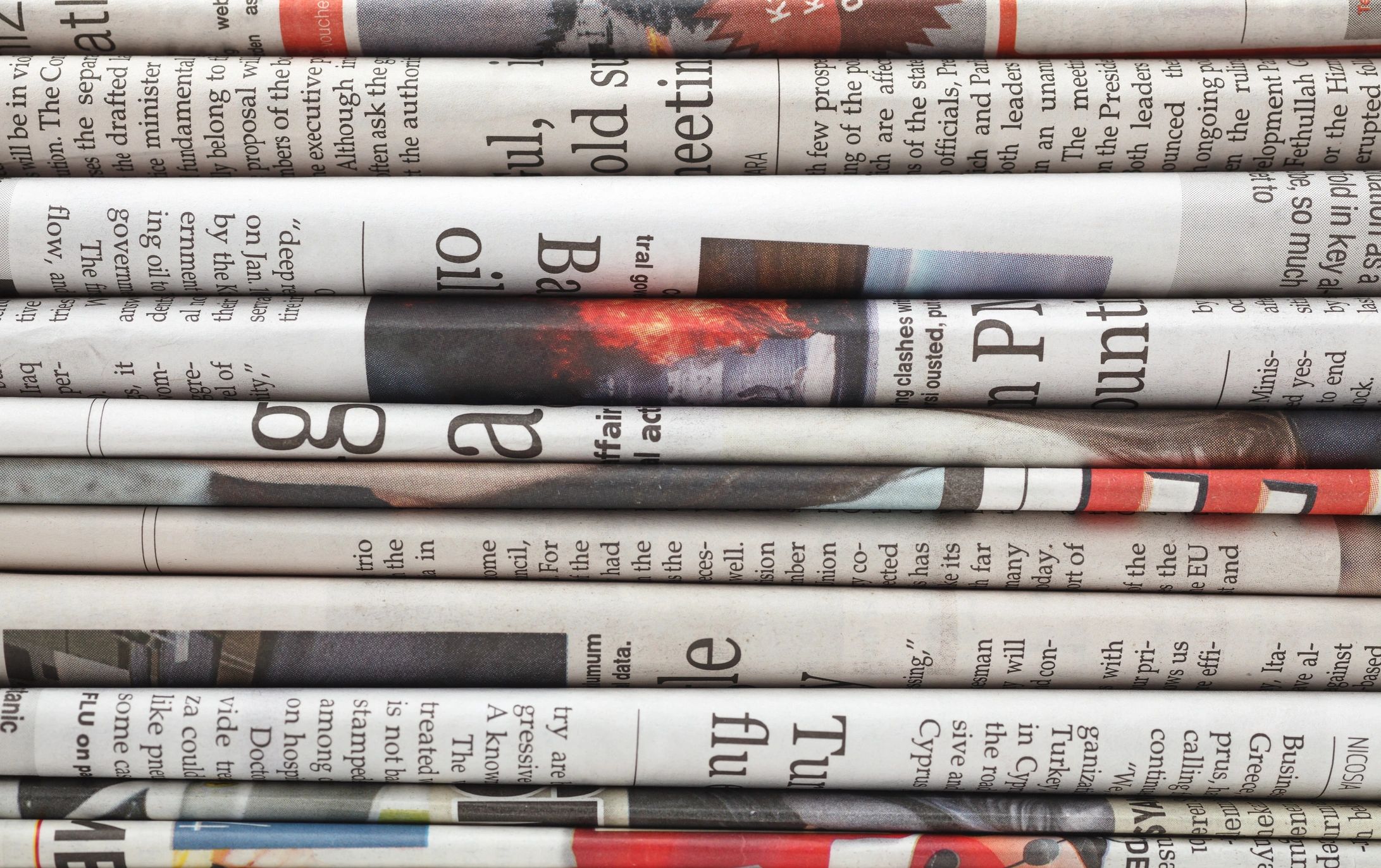 Stack of folded newspapers with visible text and images.