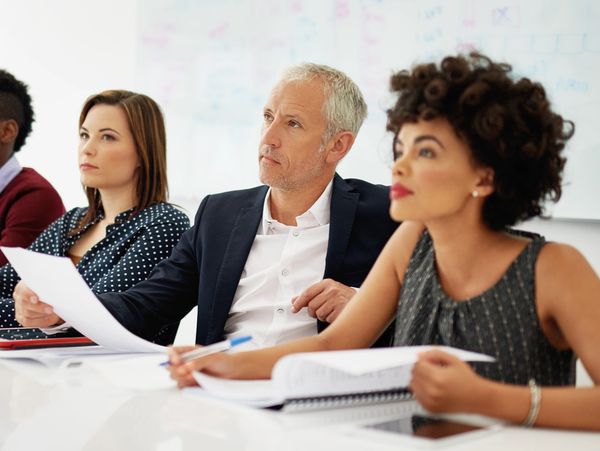 Three professionals attentively participating in a business meeting or seminar.