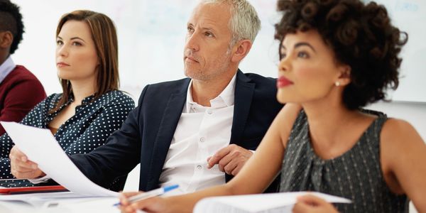 Professionals attentively participating in a business meeting around a white table.