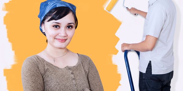 Smiling woman with a blue headscarf and a man painting a wall in the background.