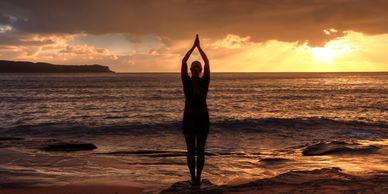 yoga pose in front of ocean at sunset
