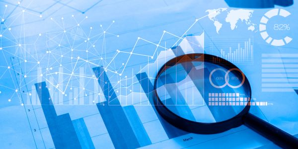 Magnifying glass analyzing financial bar charts with digital data overlays.