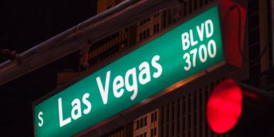 Las Vegas street sign and red traffic light at night.