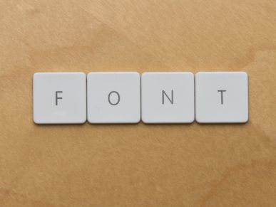 Keyboard keys spelling the word 'FONT' on a wooden surface.