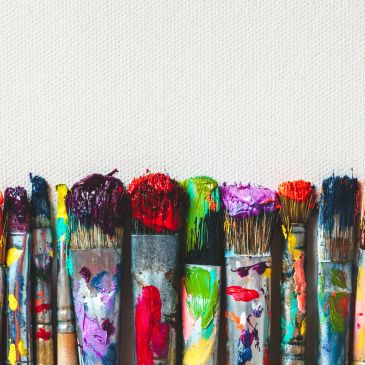 Paintbrushes with colorful paint on a white canvas background.