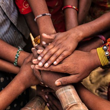 Hands of diverse people stacked together, symbolizing unity and teamwork.