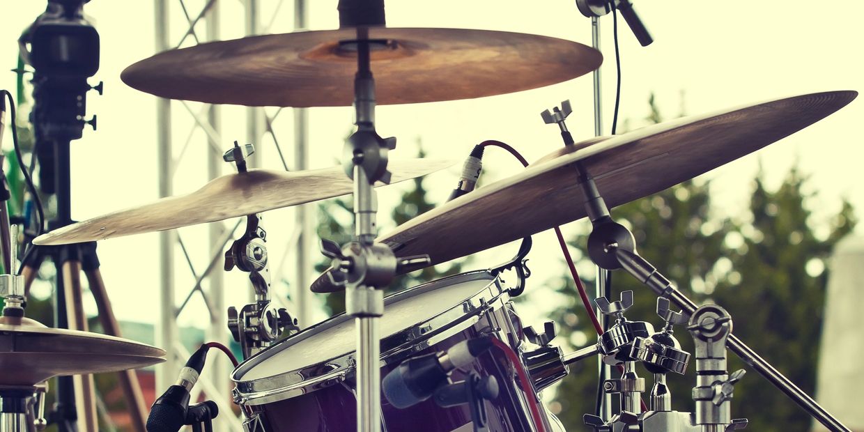 Close-up of a drum set with cymbals and microphones on stage.