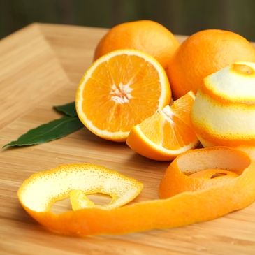 Fresh oranges, whole, sliced, and peeled on a wooden surface.