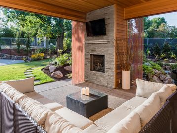 Cozy outdoor covered porch, 3-seasons room, entertaining area with seating area and an outdoor fireplace. You may never want to go back "inside" again.