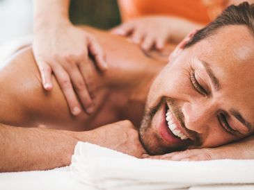 Man smiling while receiving a back massage.