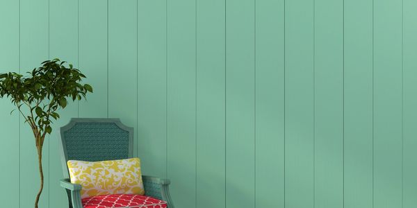 Colorful armchair and potted plant against a pastel turquoise paneled wall.