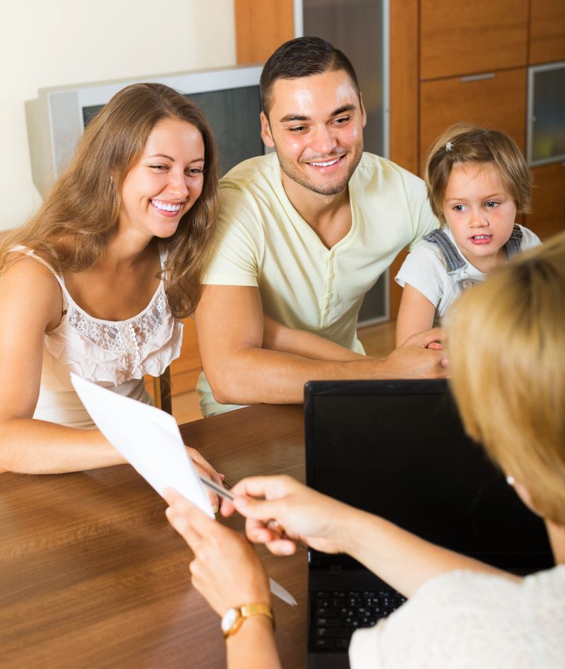 Banking assistant and smiling young family arranging mortgage details at home. Focus on woman