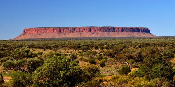 A flat-topped mesa in a desert landscape under a clear blue sky.