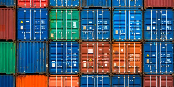 Stacked colorful shipping containers in a storage yard.