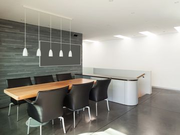 Modern conference room with wooden table and black chairs.