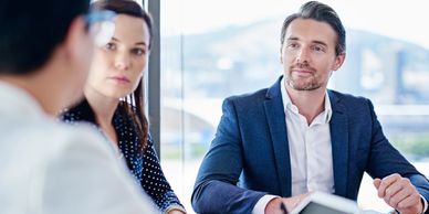 Three professionals engaged in a business meeting around a table with a tablet.