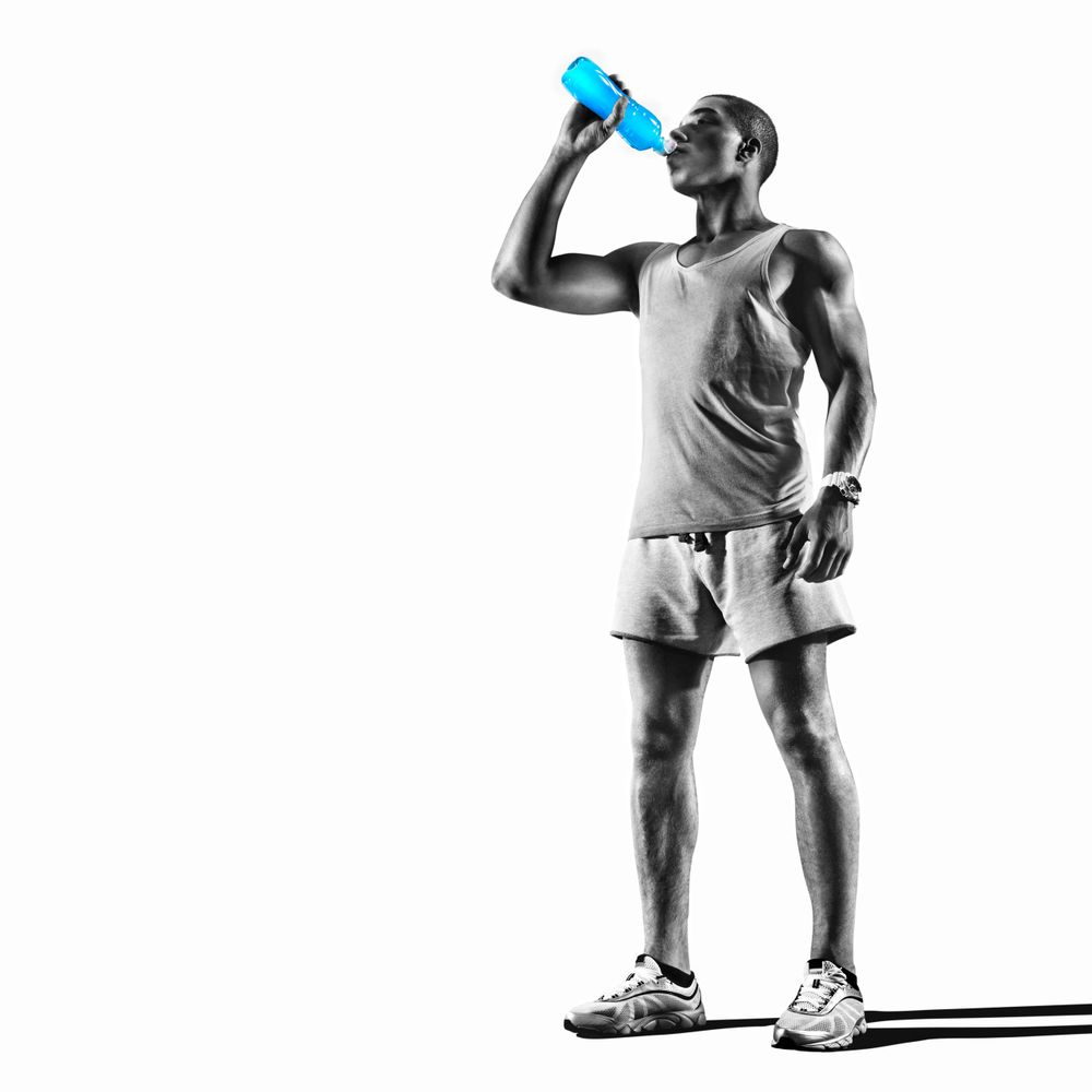 Athletic man drinking from a bright blue water bottle, dressed in workout gear.
