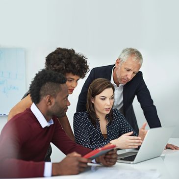 Diverse team collaborating intently around a laptop in a modern office.