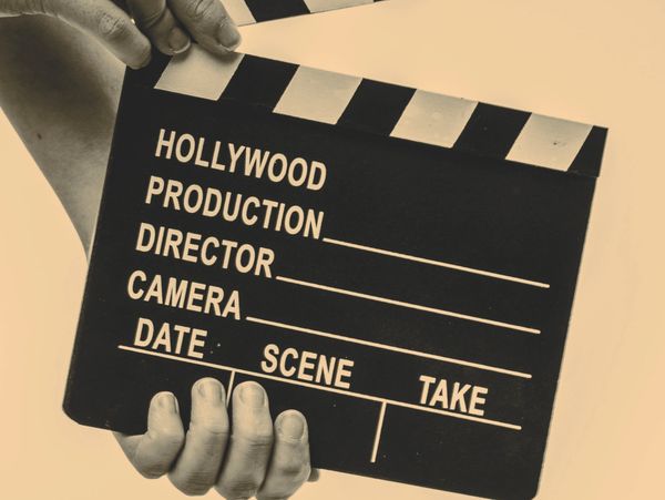 Hands holding a classic black and white film clapperboard for movie production.