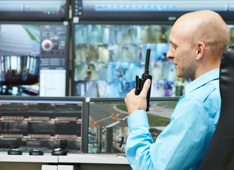 security guard watching video monitoring surveillance security system with portable radio transmitter