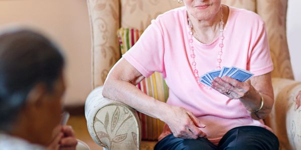 Elderly woman thoughtfully holding playing cards during a game at home.