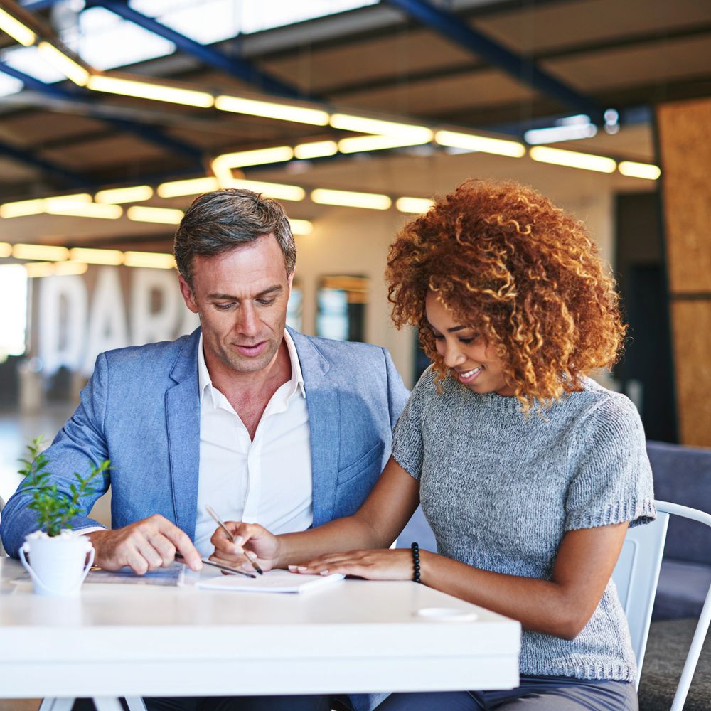 Two colleagues collaborating on a project at a modern office desk.