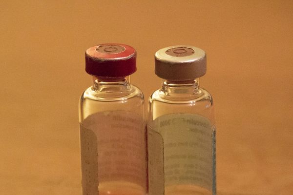 Two small glass vials with colored caps on a warm-toned surface.