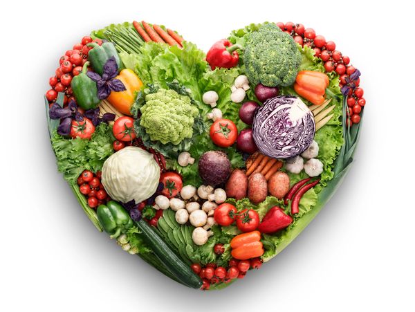 Heart-shaped arrangement of fresh vegetables on white background.