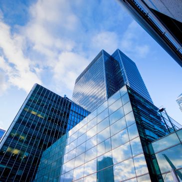 Modern skyscrapers with reflective glass facades under a blue sky.