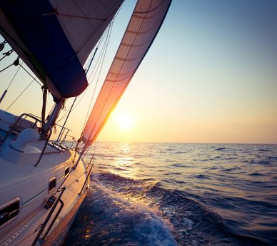 Sailboat gliding on the sea at sunset with vibrant colors.