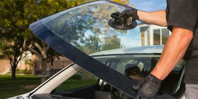 Person installing a car windshield using suction cups.