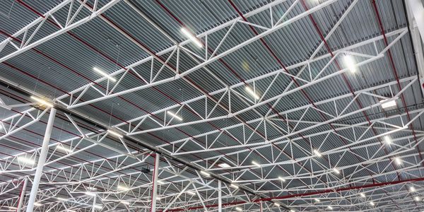 Industrial warehouse ceiling with metal beams and bright lighting.