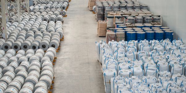 Warehouse aisle filled with organized industrial rolls and large bags.