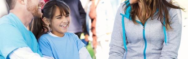 A smiling girl in a light blue shirt with a man beside her.