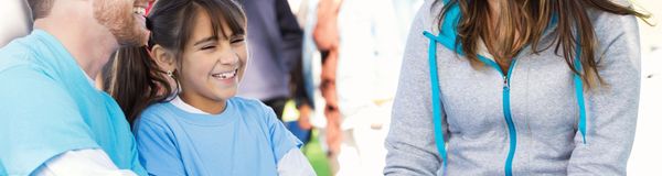 A smiling girl in a light blue shirt with a man beside her.