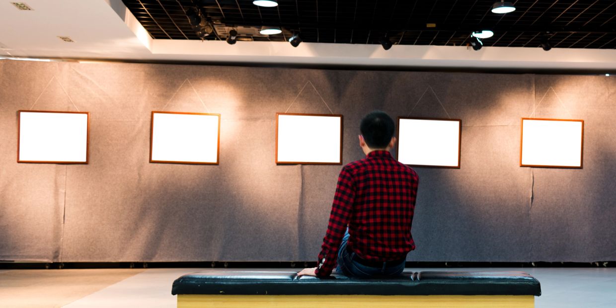 A person in a red checkered shirt sitting and viewing blank frames.