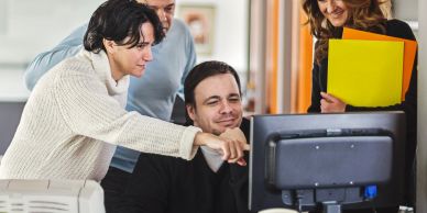 Colleagues collaborating around a computer.