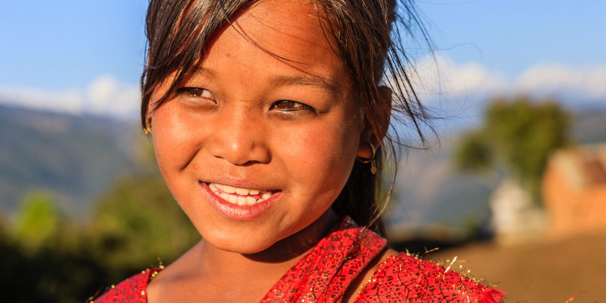 Smiling young girl outdoors with a bright red traditional outfit.