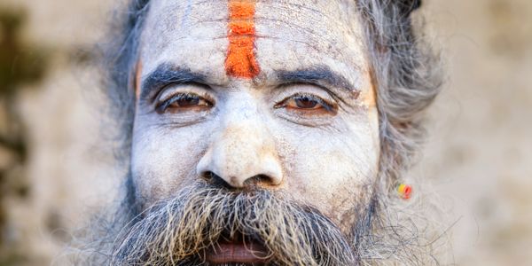 Close-up of a man with traditional face paint and a thick beard.